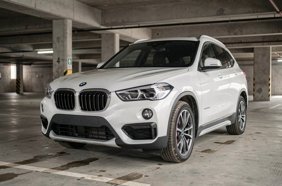 BMW X1 F48 blanc garé dans un parking urbain, vue trois quarts avant mettant en valeur la calandre et les jantes, illustration fiabilité SUV compact
