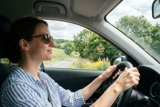 Femme en blouse rayée conduisant une voiture moderne
