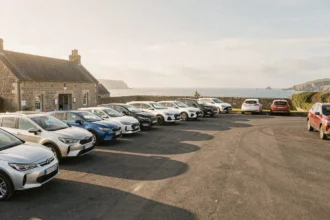 Rangée de voitures de location devant une agence en Bretagne avec vue sur la côte du Morbihan
