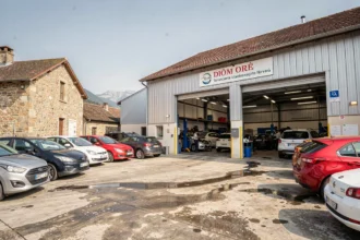 Vue extérieure d'un garage automobile dans la Drôme avec des véhicules garés devant un atelier ouvert
