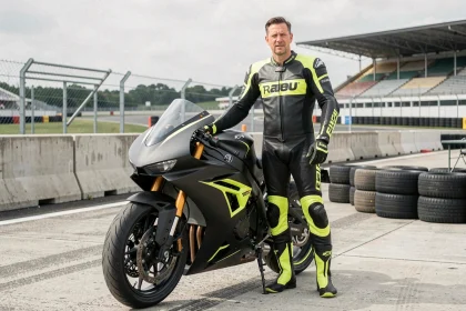 Pilote professionnel en combinaison de cuir debout à côté d'une moto superbike haute performance sur une piste de course homologuée
