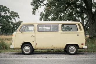 Volkswagen Type 2 T3 d'occasion garée sur le bord d'une route de campagne, carrosserie jaune pâle avec traces de rouille superficielle visibles